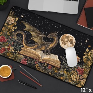 May include: A black dragon with wings outstretched sits on top of an open book with a full moon in the background. The book is surrounded by a floral design with a dark blue background and white stars. The mouse mat is 30.5 cm by 55.9 cm.