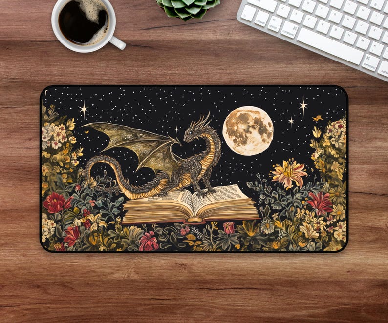 May include: A black mouse mat featuring a dark green dragon perched on an open book. The dragon has gold accents and is surrounded by a floral design. The background is a dark blue night sky with stars and a full moon.