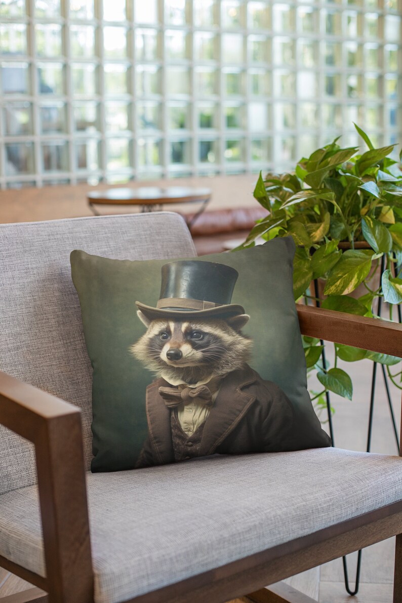 May include: A throw pillow with a vintage-style illustration of a raccoon wearing a top hat and a bow tie. The raccoon is dressed in a brown suit and has a serious expression on its face.