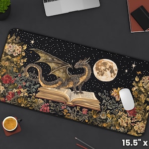 May include: A black mouse mat with a dark background featuring a dragon curled around an open book. The dragon is a dark green and gold colour with a light green underbelly. The book is open to a page with text and has a brown leather cover. The background is a dark blue with stars and a full moon. The mouse mat is 15.5 inches by 31 inches.