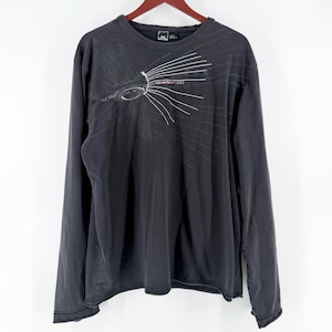 May include: A charcoal gray long-sleeve crew neck shirt featuring a white graphic design on the upper chest. The graphic includes the text Oakley 242 with radiating lines extending outward. The shirt has a ribbed neckline and a size XXL label.