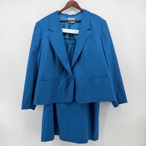 May include: A bright blue two-piece suit consisting of a long-sleeve blazer with notched lapels and two front pockets, paired with a matching skirt. The blazer features a single button closure and a smooth, solid-colored fabric construction.