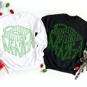 Puede incluir: Dos sudaderas, una blanca y otra negra, con un diseño gráfico verde de un cubo hecho con las palabras "Autenticación de dos factores".