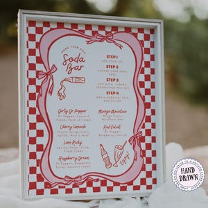 May include: A framed sign with a red and white checkered border and a pink decorative outline. The sign reads "Make Your Own Soda Bar" and lists soda recipes. The sign also includes the text "Hand Drawn".