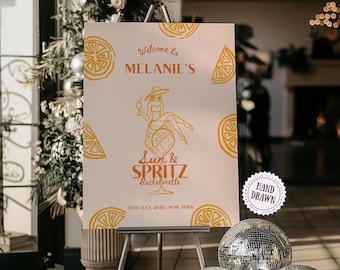 May include: A white sign with orange text and illustrations, displayed on a metal easel. The sign reads "Welcome to MELANIE'S" and "Sun & Spritz Bachelorette" with a drawing of a woman in a cocktail glass. Decorative orange slices surround the text.