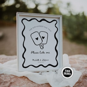 Könnte beinhalten: Ein gerahmtes Schild mit weißem Hintergrund und schwarzem Text und Rand. Der Text lautet "FOR OUR NUMBER ONE FANS" und "Please take one". Zwei Eis am Stiel-Illustrationen mit Herzdetails befinden sich in der Mitte. Das Schild ist mit Namen und Datum personalisiert.