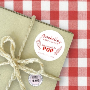 She’s Ready to Pop Baby Shower Soda Bar Style round Canva sticker template – 50s Soda Pop-Inspired. This Baby Shower sticker Template is easy to edit and print at home. It features red retro style fonts with a hand-drawn 1950s style soda bottle illustration on a white background- perfectly matching with the rest of this suite. Use for Invitation envelopes, on party paper cups, as labels for party favors and many other uses. Drag & drop templates included to easily print at home