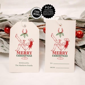 May include: Two cream-colored gift tags with a red and green illustration of a cowgirl in a martini glass, with the words "MERRY CHRISTMAS". One tag has "WITH LOVE, The Matthews Family" and the other has "TO:" and "FROM:" lines.