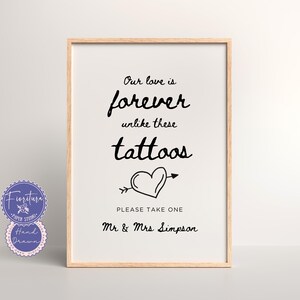 May include: A white sign with black text and a heart with an arrow through it. The text reads "Our love is forever unlike these tattoos. Please take one Mr. & Mrs. Simpson."