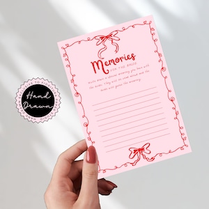 May include: A pink card with a red border and a red bow at the top. The card says "Memories for the Bride" and has lines for writing down memories.