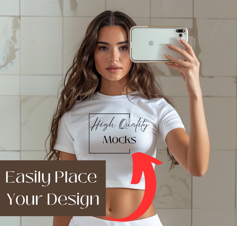 May include: A white crop top with short sleeves and the text "High Quality Mocks" printed on the front. The model is holding a white smartphone with a gold frame.