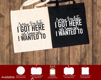 May include: Two canvas tote bags, one cream and one black, with the text "Sorry I'm late I GOT HERE as SOON as I WANTED TO" printed in black and white, respectively. Additional products include mugs, ornaments, and a hardcover journal.