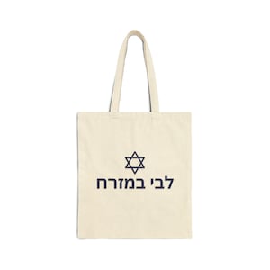 May include: A beige tote bag with a navy blue Star of David and the Hebrew text "לב במוחרה" printed on the front.