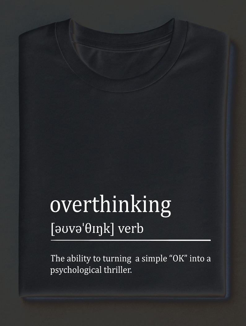 May include: Black t-shirt with the word "overthinking" in white, along with its phonetic pronunciation and definition. The definition reads: "The ability to turning a simple "OK" into a psychological thriller."