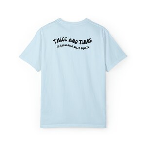 Pode incluir: Camiseta azul claro com texto preto que diz "THICC AND TIRED OF BULGARIAN SPLIT SQUATS".