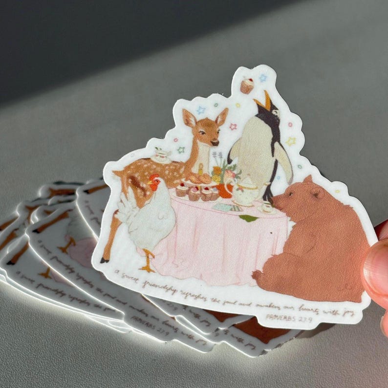 May include: A sticker featuring a whimsical illustration of a tea party with a deer, penguin, bear, and chicken around a pink table. The text reads "A sweet friendship refreshes the soul and makes our hearts with joy." Proverbs 27:9.