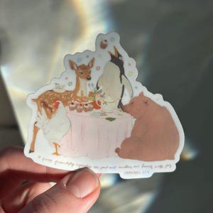 May include: A sticker featuring a whimsical tea party scene. A deer, penguin, bear, and chicken are gathered around a pink table with cupcakes and a teapot. The text reads, "A sweet friendship refreshes the soul and makes our hearts with joy." Proverbs 27:9.