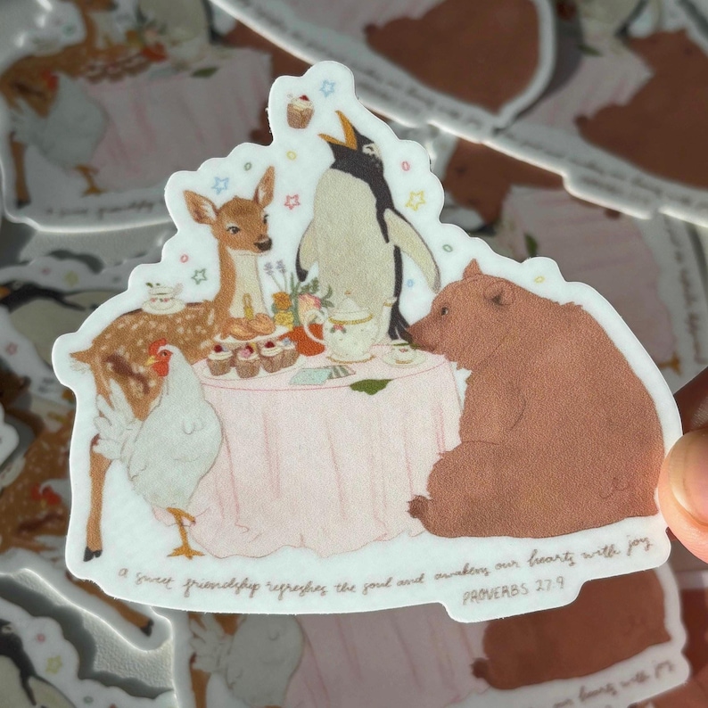 May include: A sticker featuring a whimsical tea party scene with a deer, penguin, bear, and chicken around a pink table. The sticker has a white border and includes the text "A sweet friendship refreshes the soul and awakens our hearts with joy PROVERBS 27:9."