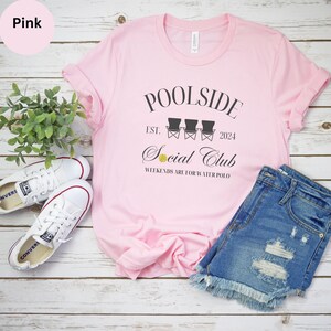 Pode incluir: Camiseta rosa com o texto "Poolside Social Club Est. 2024" e um gr&aacute;fico de tr&ecirc;s cadeiras de praia e uma bola de voleibol. O texto "Weekends are for water polo" tamb&eacute;m est&aacute; na camiseta.