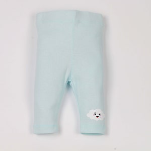 May include: Light blue baby leggings with a white cloud with a smiling face on the right leg.