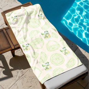 May include: A white beach towel with a repeating pattern of green lime slices and cocktails with lime wedges and green herbs.