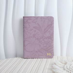 以下が含まれることがあります： ラベンダー色の革製のジャーナルで、花柄がエンボス加工されています。ジャーナルの表紙には、金色のエンボス加工で「FG」のモノグラムが施されています。