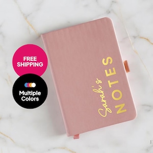 May include: A blush pink notebook with a gold inscription that reads "Sarah's Notes".