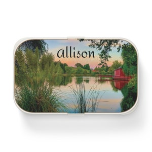 May include: A white rectangular box with a wooden lid featuring a scenic image of a lake with trees and a red building. The text "allison" is printed on the lid.