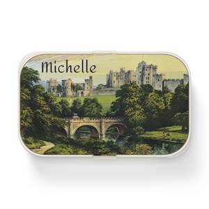 May include: A white rectangular box with a colorful image of a castle and a bridge. The text "Michelle" is printed on the box.