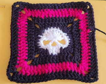 Peut inclure: Un carré de crochet noir et blanc avec une bordure rose. Le centre du carré présente un motif de crâne blanc.