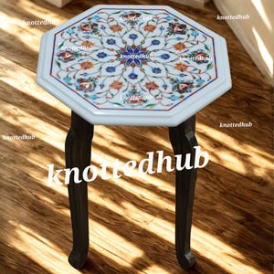May include: A white marble side table with an octagonal top featuring a floral inlay design in shades of red, blue, and orange. The table has dark brown, curved legs, and is suitable for indoor use.