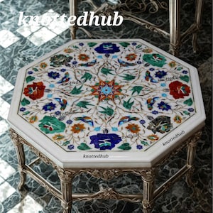 May include: Octagonal white marble table with intricate floral inlay in red, blue, green, and orange. The table has a decorative metal base with ornate detailing. The text "knottedhub" is visible on the table.