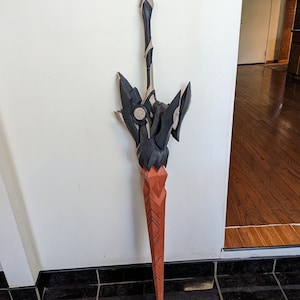 May include: A large, black and orange, intricately designed spear with a sharp point. The spear is made of a hard, durable material and has a detailed, textured surface.