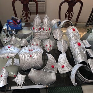 Op de afbeelding: Een set zilverkleurige bepantsering met rode accenten. De bepantsering is gemaakt van een lichtgewicht materiaal en is ontworpen om te worden gedragen voor cosplay of theatervoorstellingen.