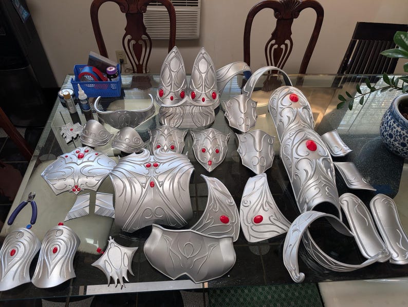 Op de afbeelding: Een set zilverkleurige bepantsering met rode accenten. De bepantsering is gemaakt van een lichtgewicht materiaal en is ontworpen om te worden gedragen voor cosplay of theatervoorstellingen.