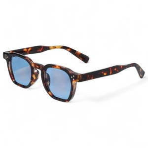 Puede incluir: Gafas de sol cuadradas con estampado de carey y lentes azules. Las gafas de sol tienen un diseño clásico con una combinación de colores marrón oscuro y ámbar. Las lentes son de color azul reflectante.