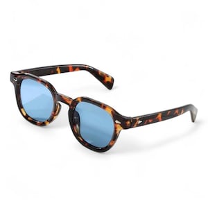 May include: Tortoiseshell-patterned sunglasses with blue lenses. The frames have a classic, angular shape. The arms of the sunglasses are also tortoiseshell, with a textured design near the hinges. The lenses are a bright, solid blue.