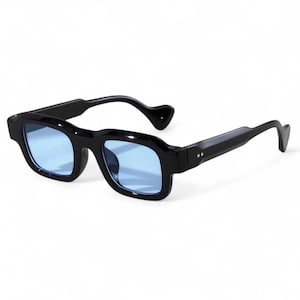 Peut inclure: Lunettes de soleil noires avec des verres bleus. Les montures carrées ont un design épais et audacieux. Les branches sont légèrement incurvées et les branches sont de couleur noire unie. Les verres sont d'un bleu vif et uni.
