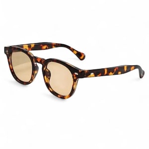 May include: Round sunglasses with a tortoiseshell pattern. The frames are brown and amber, with light brown lenses. The sunglasses have a classic, retro style.