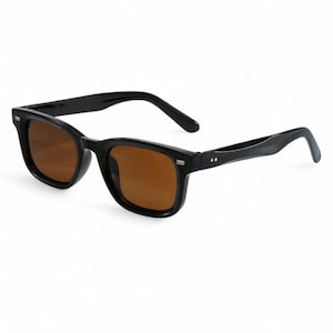May include: Black sunglasses with brown lenses. The sunglasses have a classic rectangular frame design. The arms of the sunglasses are slightly curved for a comfortable fit. The lenses are a warm brown colour, providing a contrast to the black frame.