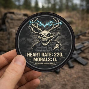 Könnte beinhalten: Ein runder, schwarzer Aufnäher mit einem Totenkopf mit Hirschgeweih und einer Waffe. Der Totenkopf hat ein bedrohliches Grinsen und ist von einem blauen Blitzmuster umgeben. Der Text auf dem Aufnäher lautet: "HEART RATE: 220. MORALS: 0. OPERATION: CARDIAC ARREST."
