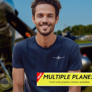 May include: Navy blue t-shirt with a small white graphic of an airplane and the text "P-51 MUSTANG" on the chest. The shirt is worn by a person smiling in front of a blurred airplane and blue sky. A yellow banner reads "MULTIPLE PLANES!"