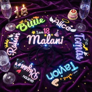 Puede incluir: Una colección de diademas iluminadas y letreros decorativos para una celebración de cumpleaños. Las diademas presentan nombres como "Malani" y "Tavion", con luces LED. Otros letreros incluyen nombres como "Billie" y "Alice". El fondo es un paño de terciopelo morado.