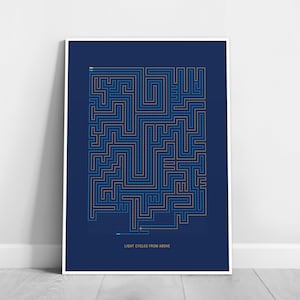 May include: A framed art print with a maze design in blue and gold on a navy background. The artwork includes the text "LIGHT CYCLES FROM ABOVE" at the bottom. The maze has a starting and ending point.