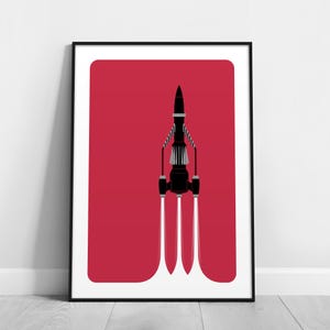 Könnte beinhalten: Gerahmter Kunstdruck mit einer schwarzen Rakete vor rotem Hintergrund. Die Rakete hat weiße und graue Details mit drei weißen Abgasfahnen. Das Kunstwerk ist im minimalistischen Stil gehalten.