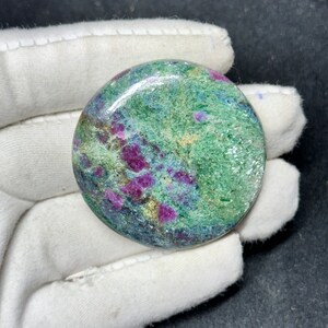 May include: A round, polished green, pink, and gold gemstone with a swirling pattern.