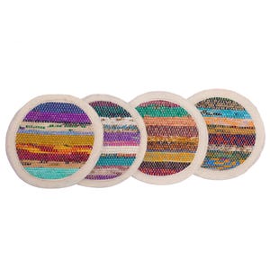 Op de afbeelding: Vier ronde onderzetters met een geweven ontwerp. Elke onderzetter heeft een uniek patroon van kleurrijke horizontale strepen in tinten blauw, paars, geel en groen. De onderzetters hebben een crèmekleurige rand.