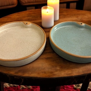 Può includere: Due porta incensi in ceramica, uno bianco con bordo marrone e uno azzurro con bordo marrone, su un tavolo di legno.