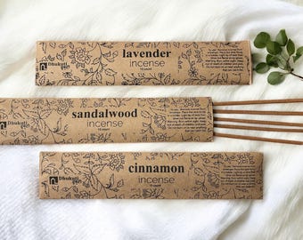 May include: Three brown cardboard boxes with black floral designs and white text. The boxes contain incense sticks in the scents of lavender, sandalwood, and cinnamon. Each box has a 15-count of incense sticks.