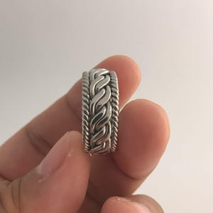 May include: A silver braided ring with a wide band.